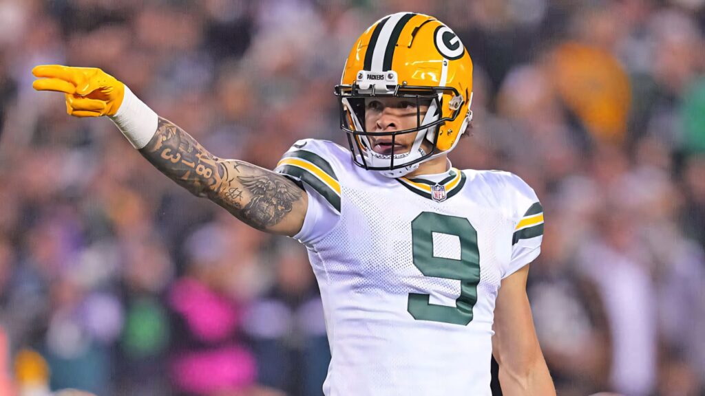 Christian Watson Green Bay Packers in green and gold uniform pointing confidently on football field wallpaper