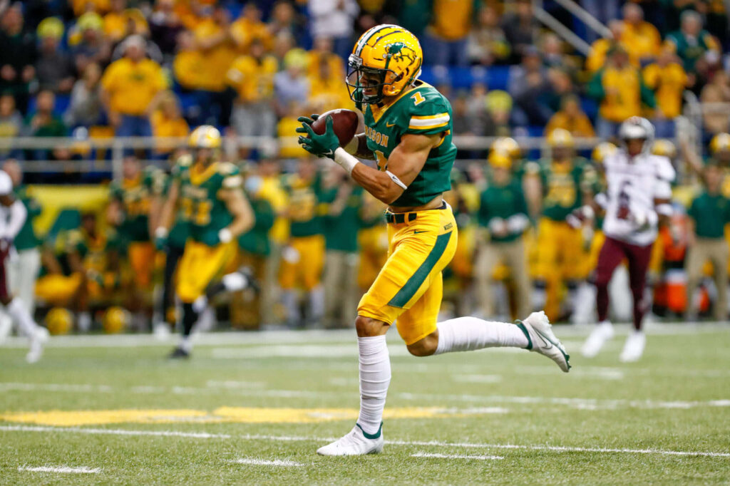 Christian Watson making a dynamic football catch in green and yellow uniform during intense game action Wallpaper