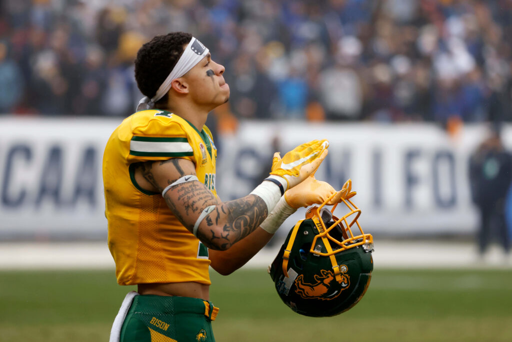 Christian Watson in yellow football uniform with helmet reflecting on field during game pause Wallpaper