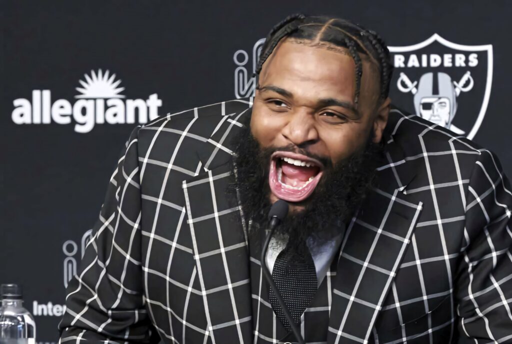 Christian Wilkins laughing energetically in black white checkered suit at Raiders press conference Wallpaper