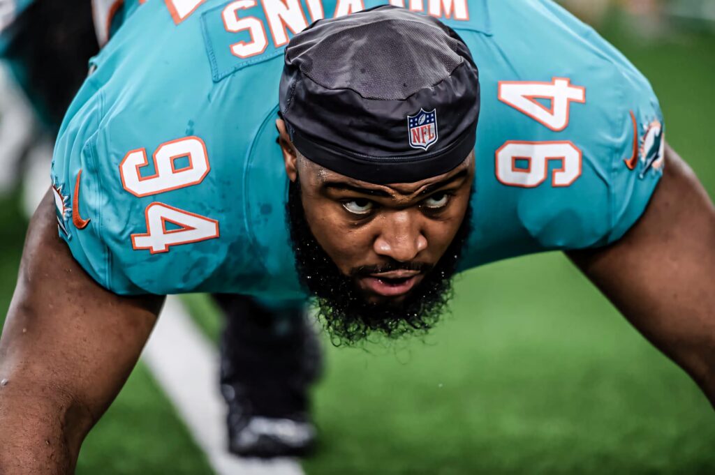 Christian Wilkins in teal Miami Dolphins uniform poised defensively focused on football field close-up Wallpaper