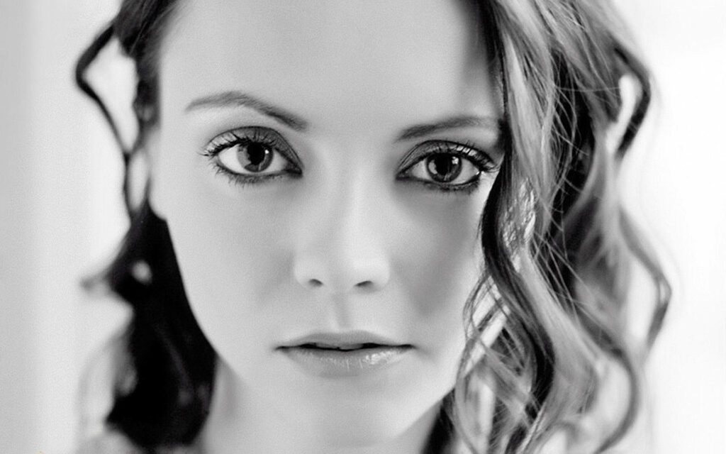 Grayscale close-up portrait of Christina Ricci with captivating eyes and softly curled hair wallpaper