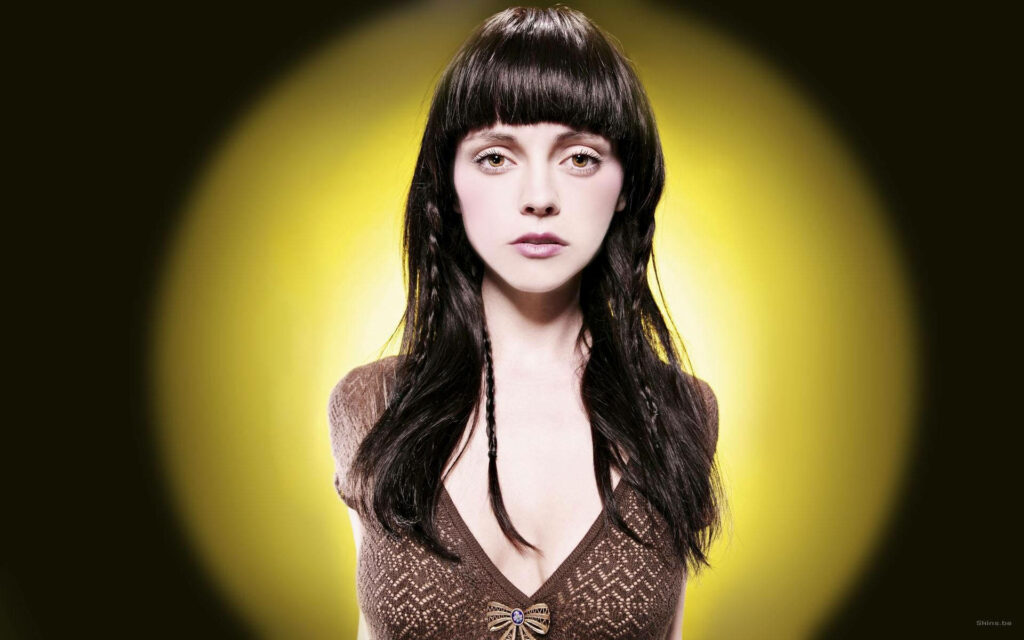 Christina Ricci portrait with glowing yellow background highlighting dark hair and expressive features Wallpaper