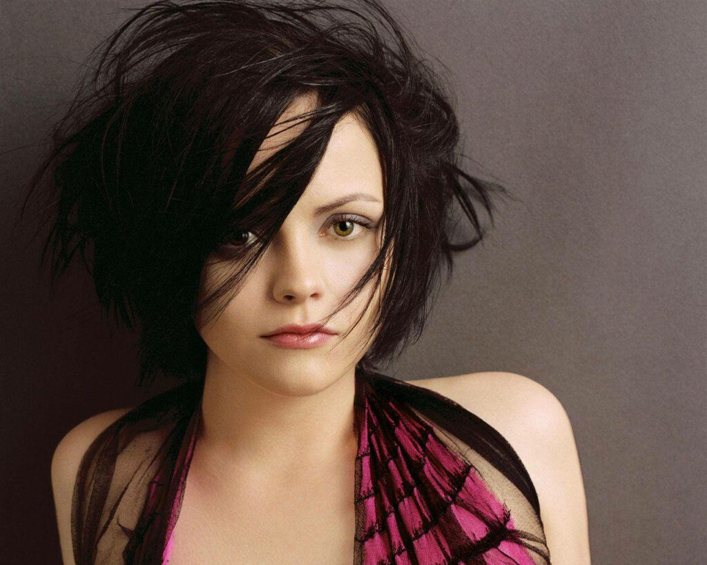Christina Ricci with short tousled hair stylish modern look against neutral wallpaper background
