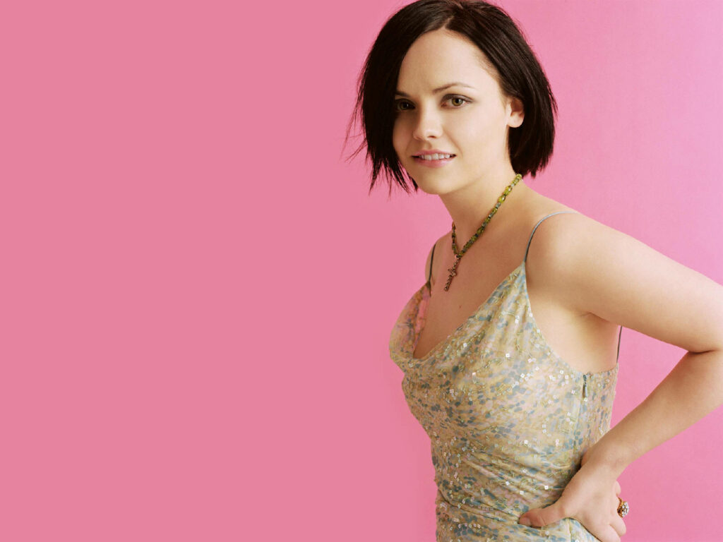 Christina Ricci in sparkling light dress and delicate necklace against solid pink background Wallpaper