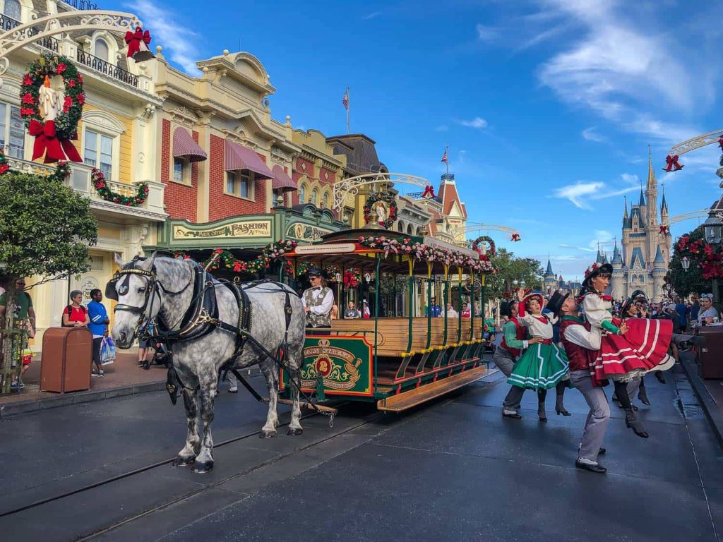 Festive Main Street Trolley at Disney World Magic Kingdom with horse dancers and Cinderella Castle Christmas decorations Wallpaper