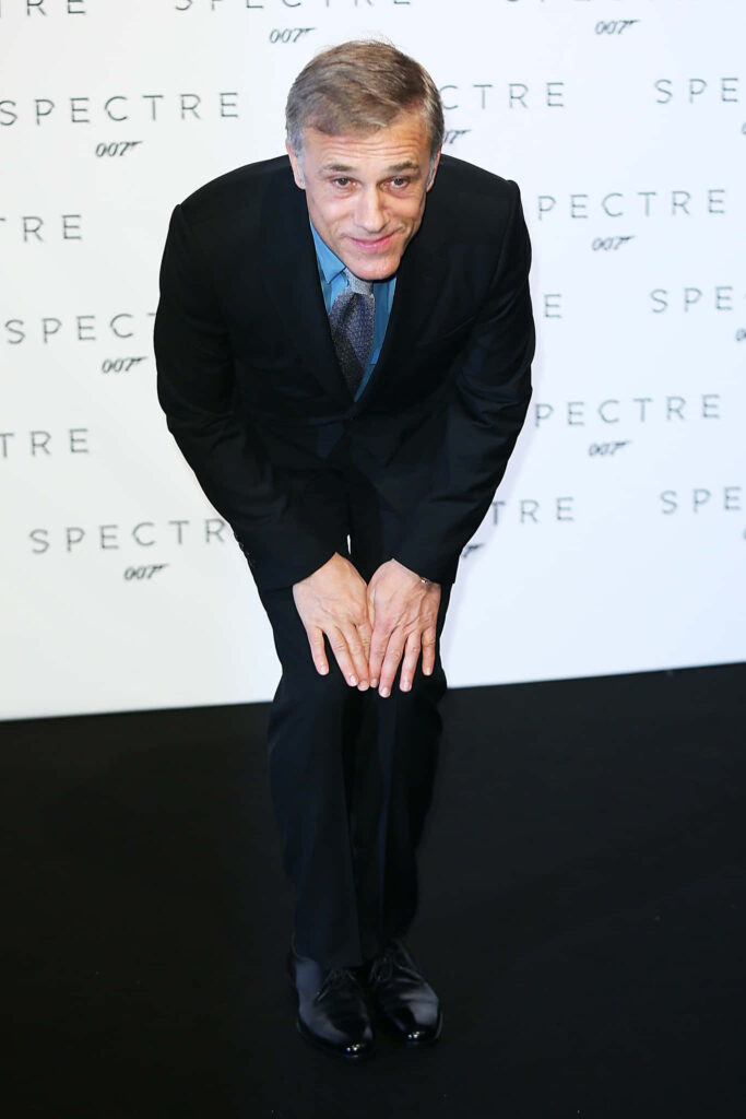 Christoph Waltz in sharp dark suit on black carpet with Spectre 007 logo background wallpaper