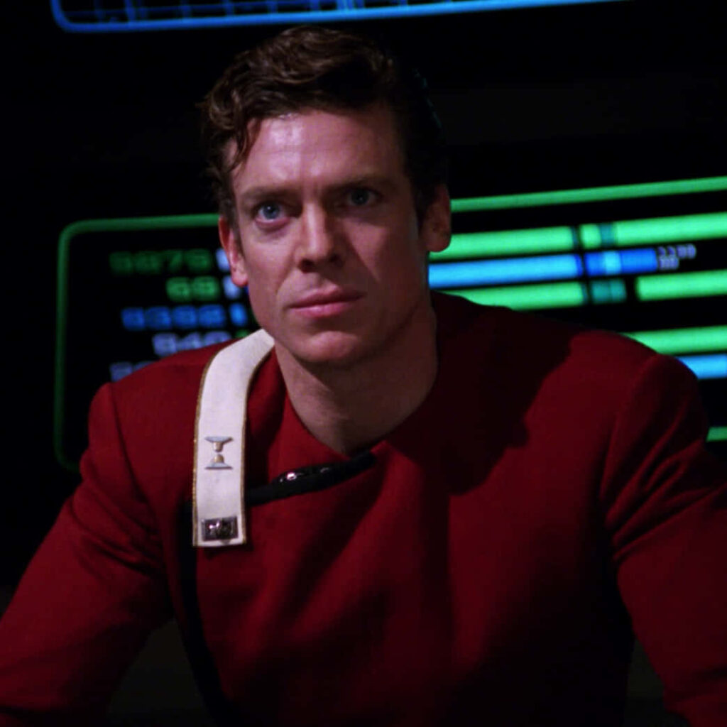 Christopher McDonald in red sci fi uniform with glowing control panels futuristic wallpaper