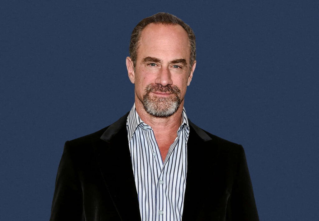 Christopher Meloni in black velvet jacket and striped shirt on navy background wallpaper