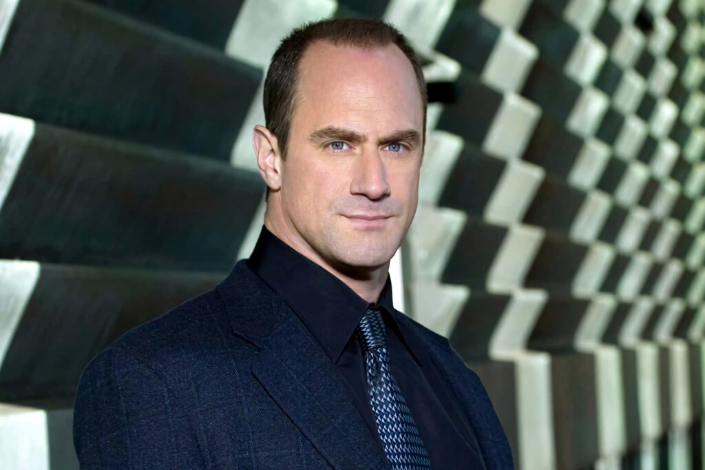 Christopher Meloni in sharp suit against modern gray 3D block pattern high resolution wallpaper