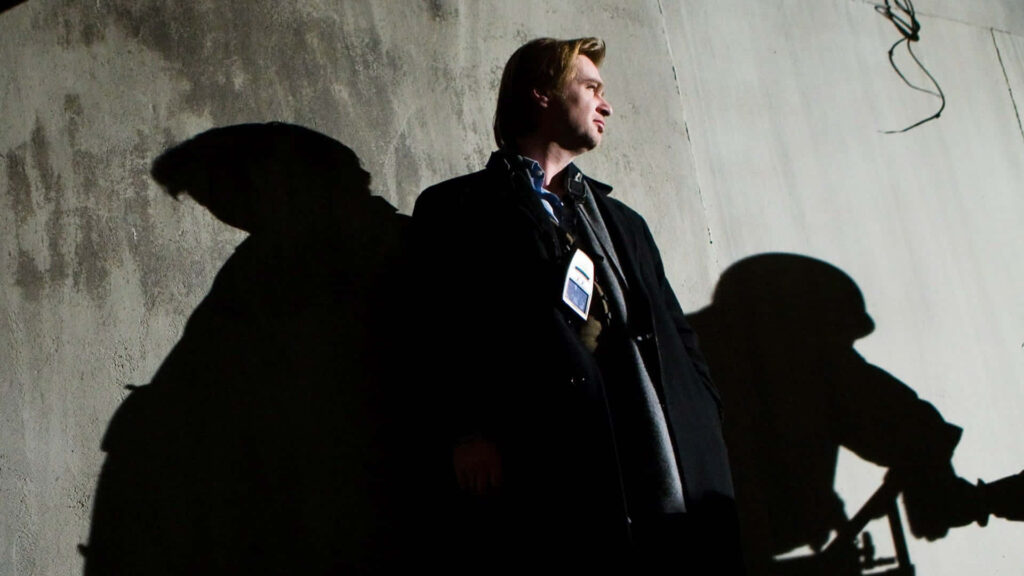 Christopher Nolan portrait with dramatic lighting and shadow on concrete wall cinematic wallpaper