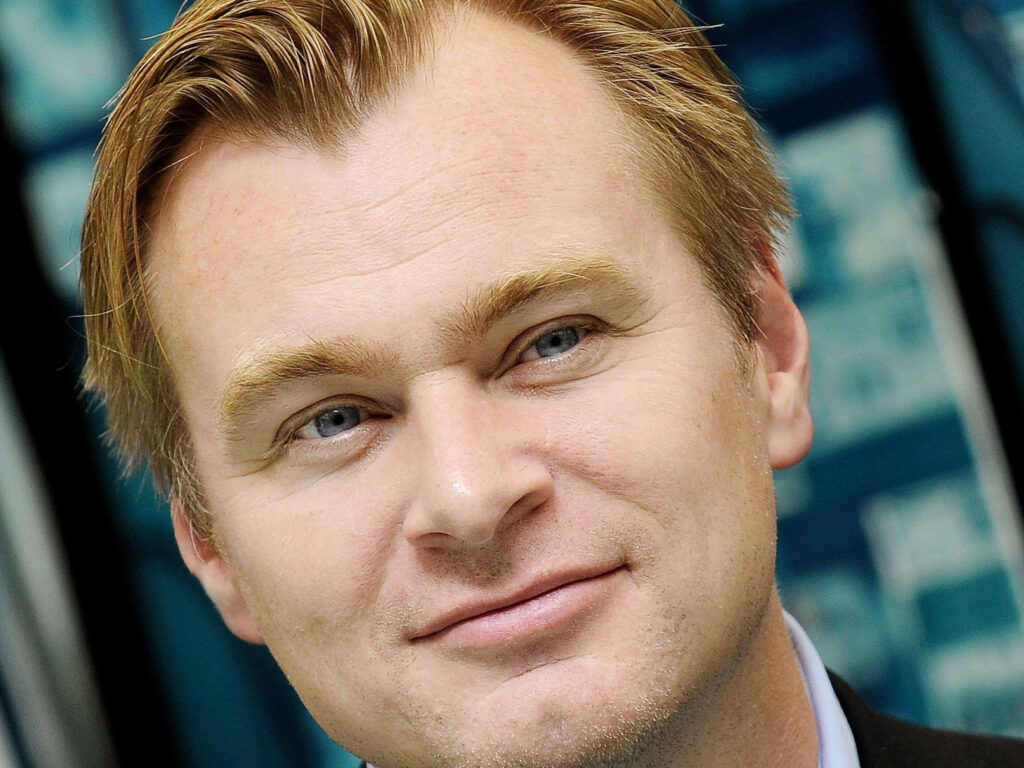 Christopher Nolan thoughtful close-up portrait with soft lighting and blurred blue background wallpaper