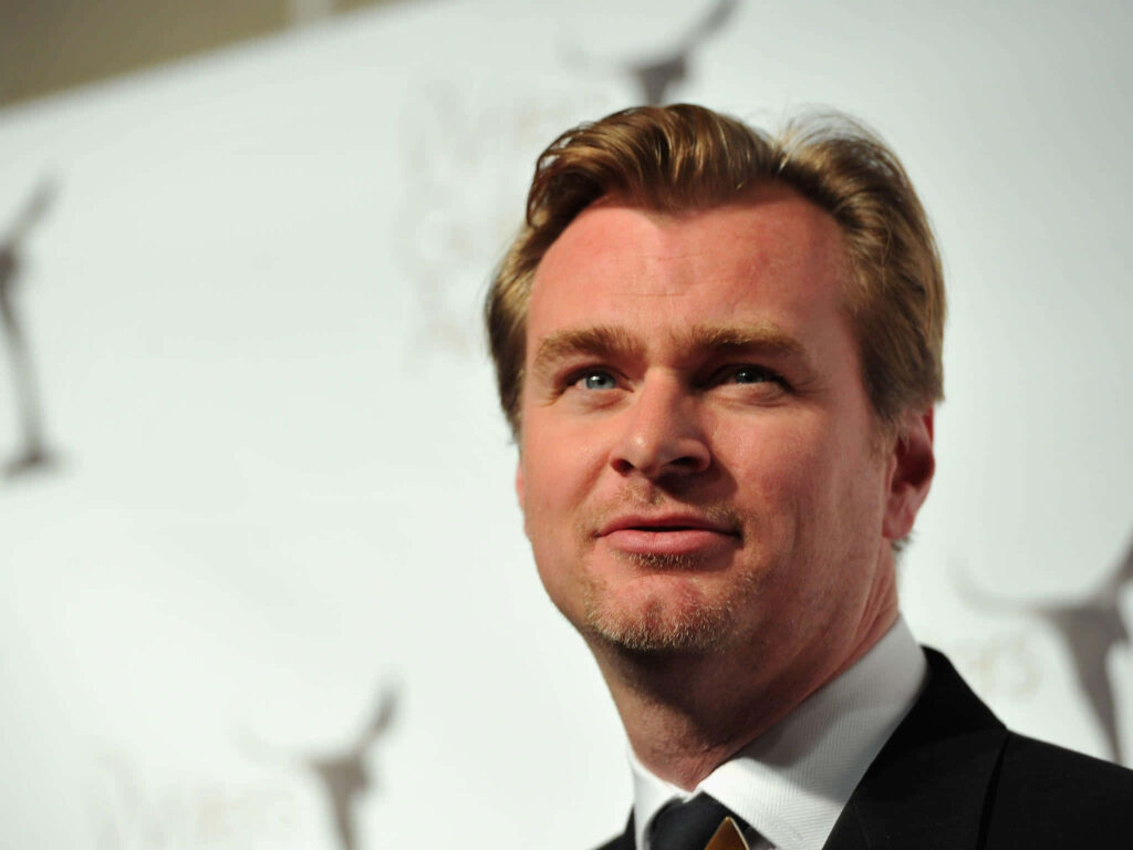 Christopher Nolan on film set in professional attire with natural lighting and cinematic background Wallpaper