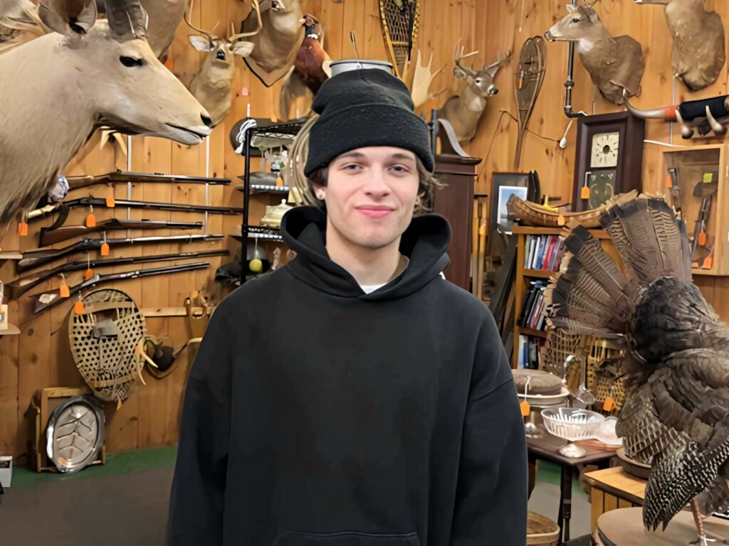 Christopher Sturniolo in rustic room with mounted animal heads vintage firearms and antique decor Wallpaper