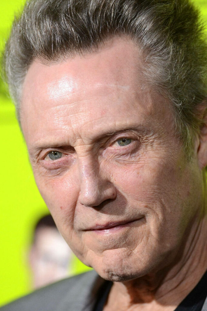 Close-up portrait of Christopher Walken with intense gaze vibrant yellow-green background wallpaper