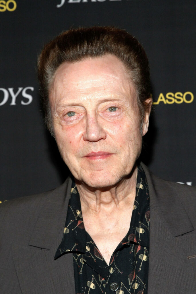 Christopher Walken in dark suit standing confidently against black backdrop sharp detailed portrait Wallpaper