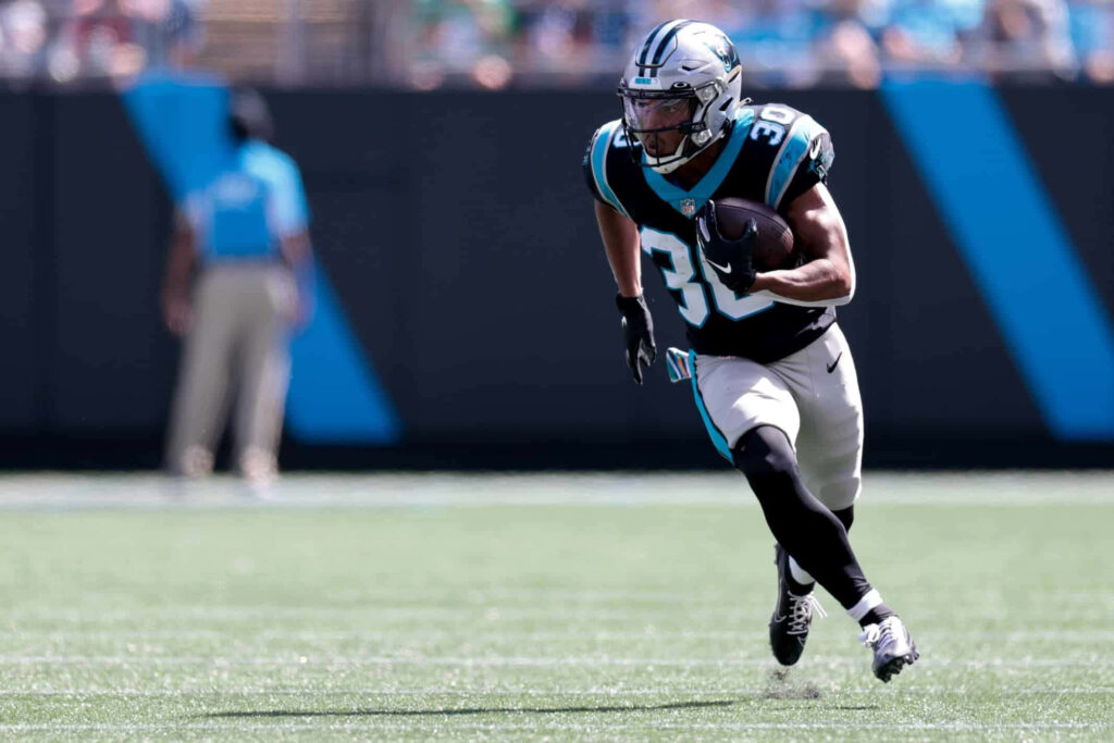 Chuba Hubbard of Carolina Panthers rushing with football showcasing athleticism in team colors Wallpaper