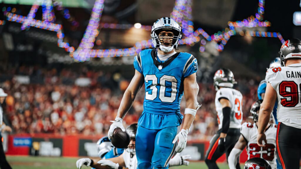 Chuba Hubbard in Carolina Panthers uniform running with football in vibrant NFL game stadium Wallpaper