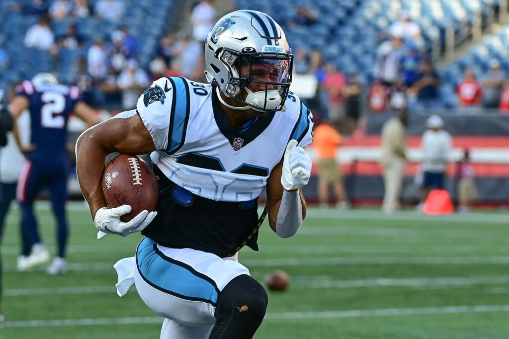 Chuba Hubbard running with ball in Carolina Panthers uniform during intense football game action Wallpaper