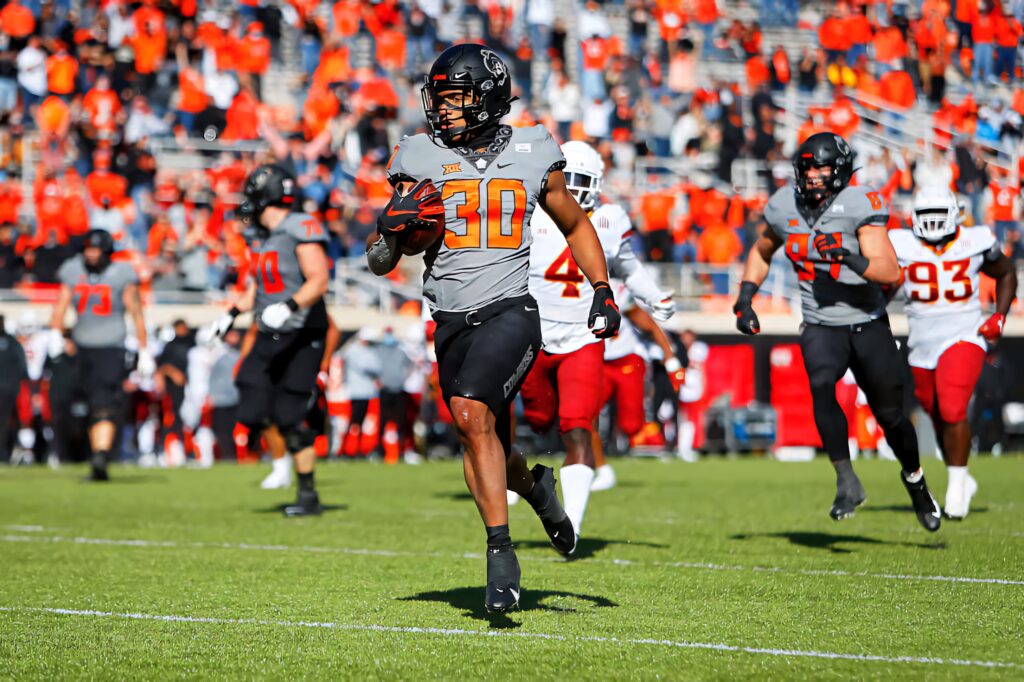 Chuba Hubbard sprinting in Oklahoma State Cowboys uniform football action vibrant stadium fans Wallpaper