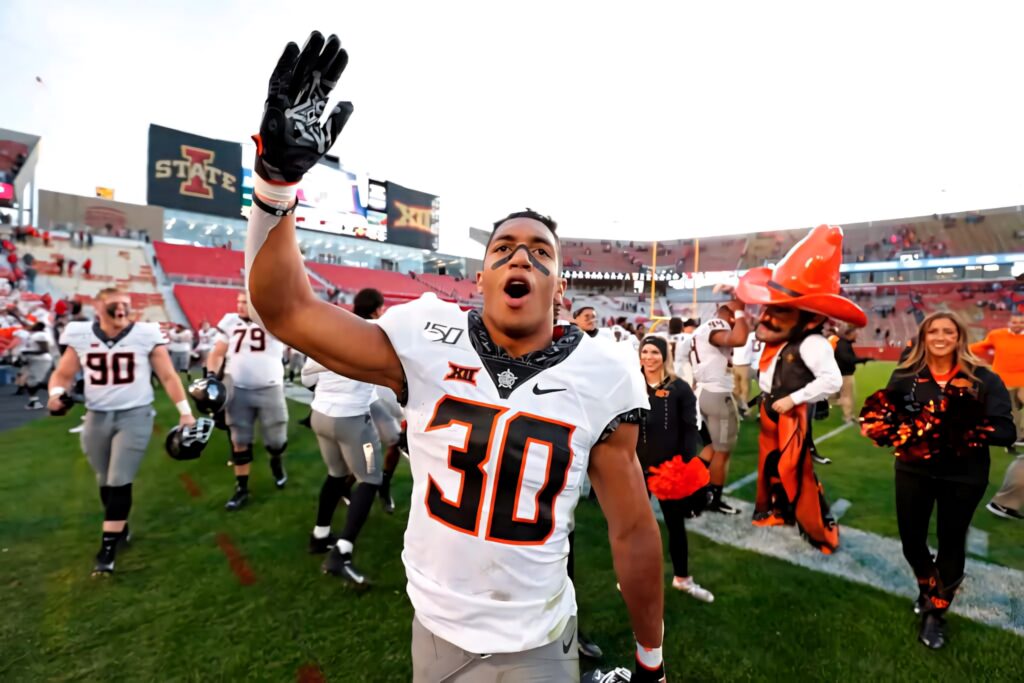 Chuba Hubbard celebrating victory in Oklahoma State Cowboys uniform with fans and team cheering Wallpaper