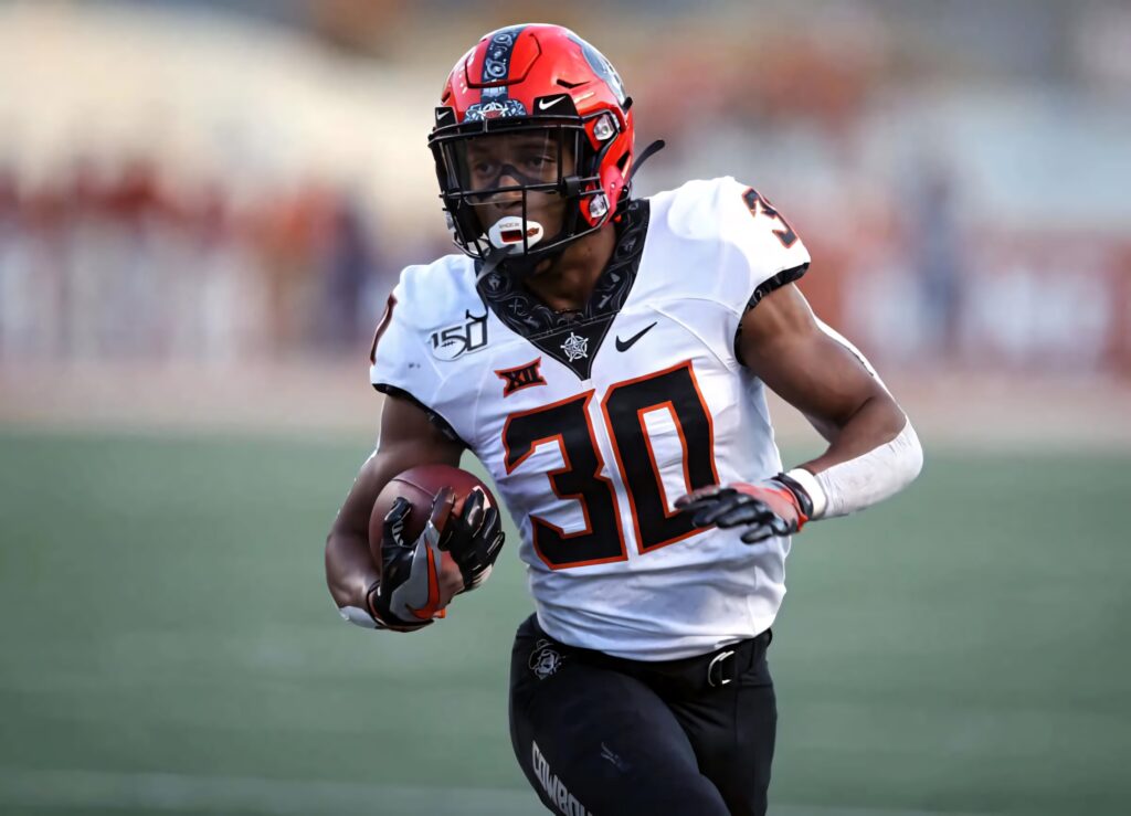 Chuba Hubbard in Oklahoma State uniform sprinting on field showing speed power and focus Wallpaper