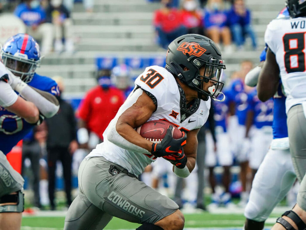 Chuba Hubbard running back charging past defenders in Oklahoma State orange gray white jersey Wallpaper