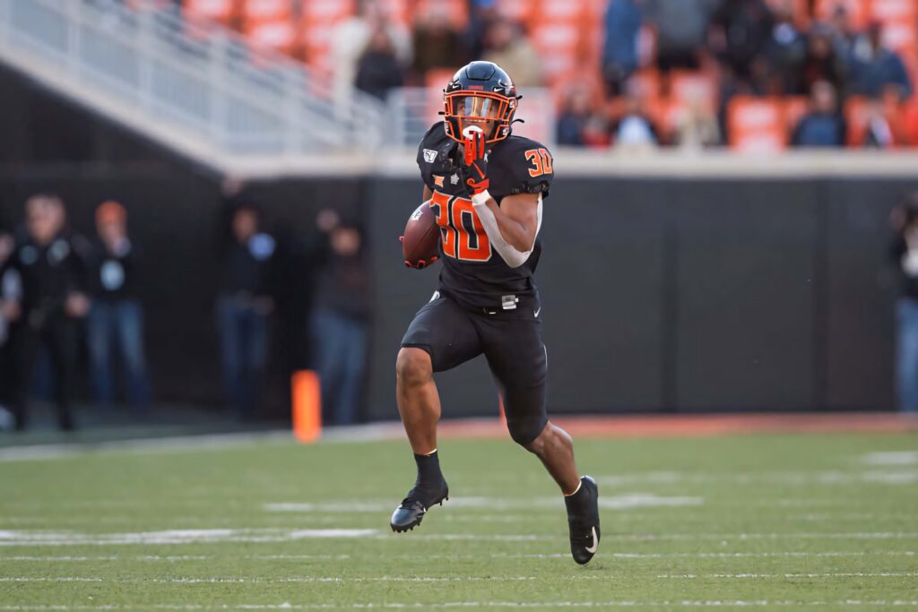 Chuba Hubbard running in Oklahoma State uniform mid-game showcasing athleticism and speed Wallpaper