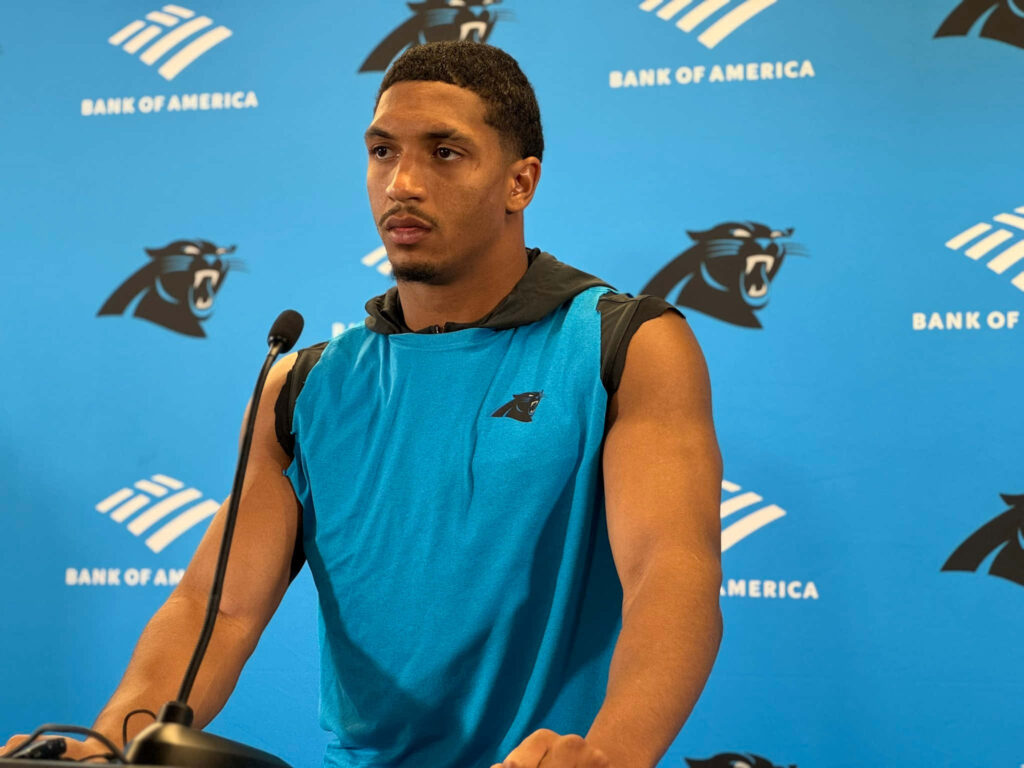 Chuba Hubbard at Panthers press conference in sleeveless hoodie with team and sponsor logos Wallpaper