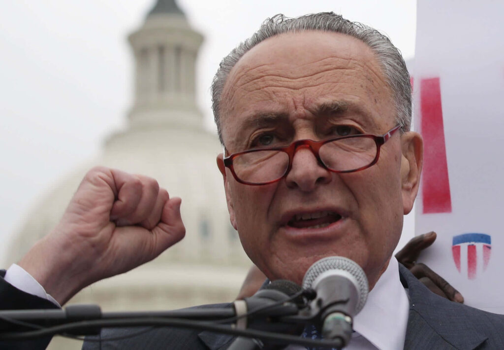 Chuck Schumer speaking passionately with raised fist at US Capitol dome political leadership background Wallpaper
