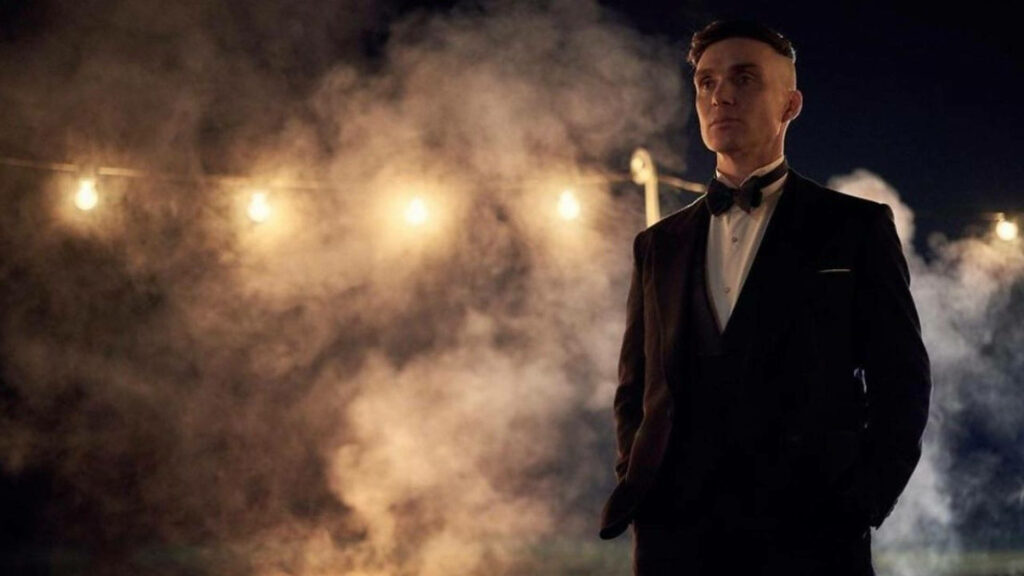Cillian Murphy in sharp suit stands confidently with glowing lights and thick fog at night Wallpaper