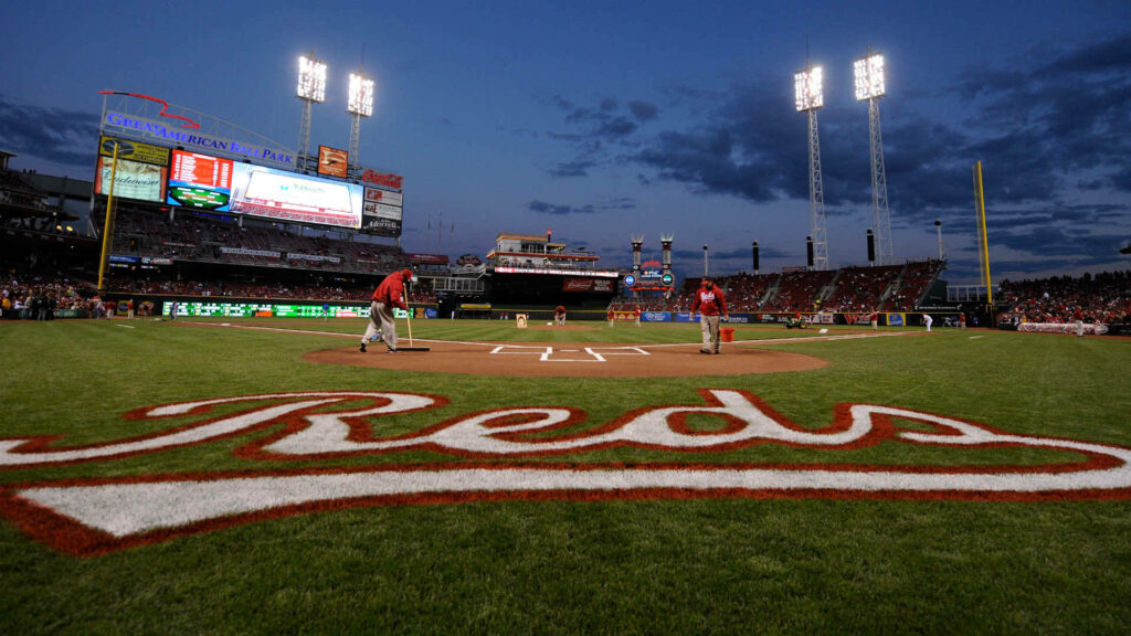 Cincinnati Reds ballpark at dusk with vibrant green field illuminated lights and bold Reds logo Wallpaper