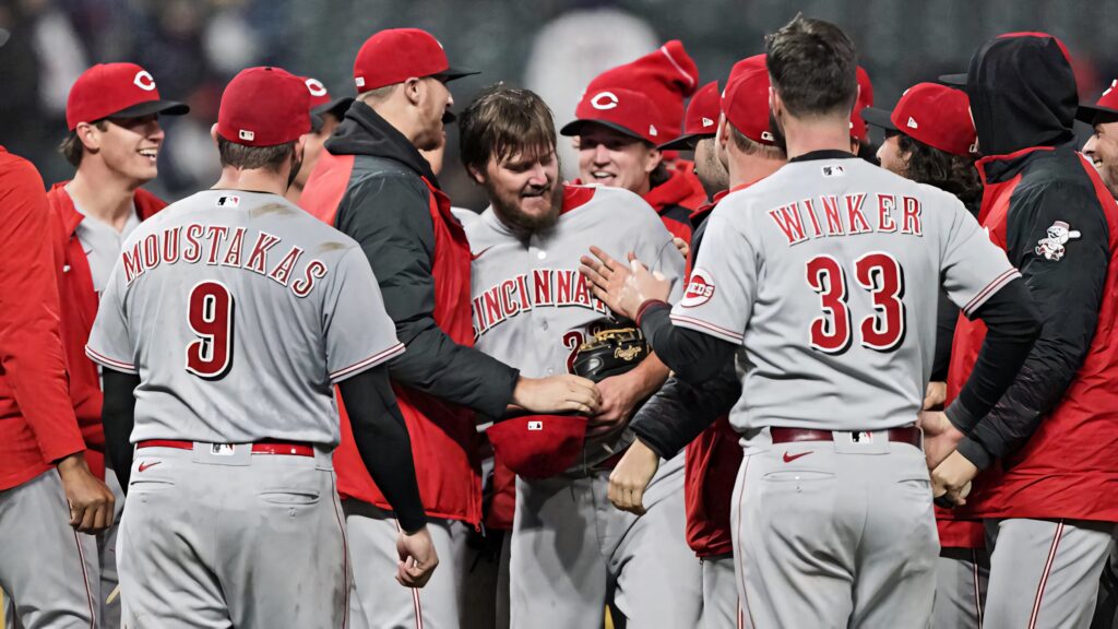 Cincinnati Reds players celebrating on field in red and gray uniforms during night game wallpaper