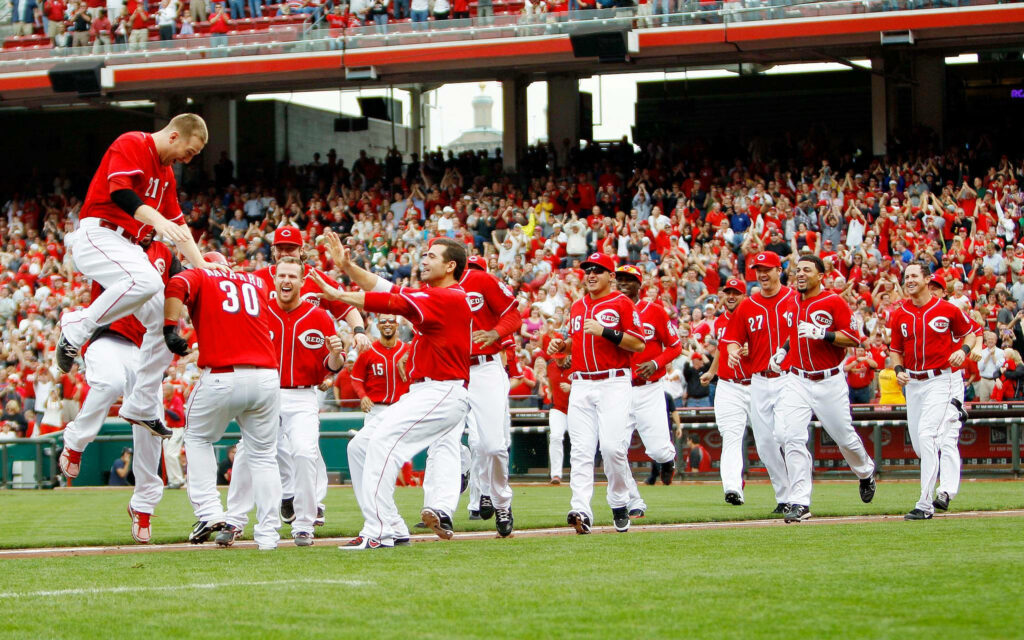 Cincinnati Reds players celebrate on field in red uniforms with cheering crowd wallpaper background