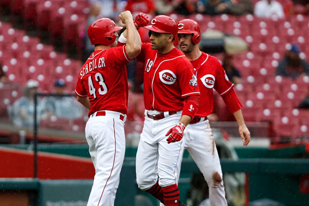 Cincinnati Reds players celebrating on field in bold red uniforms against stadium backdrop Wallpaper