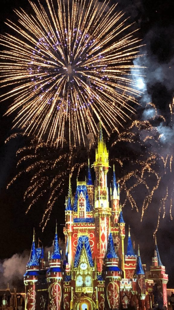 Cinderella Castle at Disney World lit in blue and gold with golden fireworks at night wallpaper