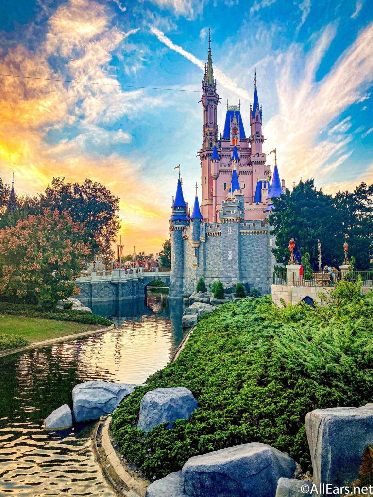 Cinderella Castle at Walt Disney World glowing pink and blue at sunset over calm moat wallpaper
