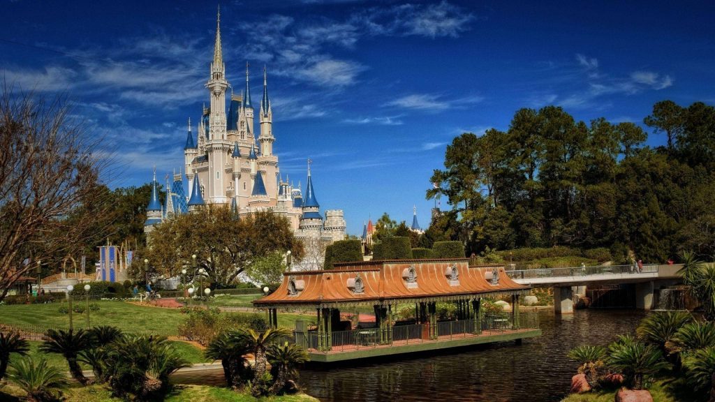Cinderella Castle side view at Walt Disney World bright sunny day with blue sky and waterfront Wallpaper