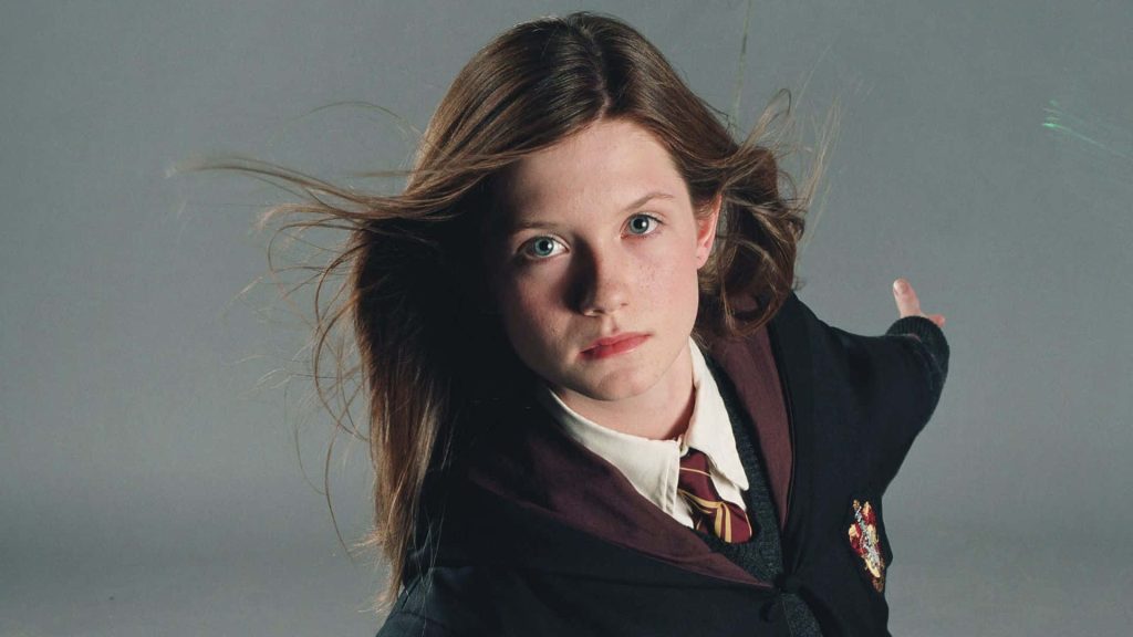 Bonnie Wright as Ginny Weasley in Gryffindor robes intense gaze cinematic Harry Potter wallpaper