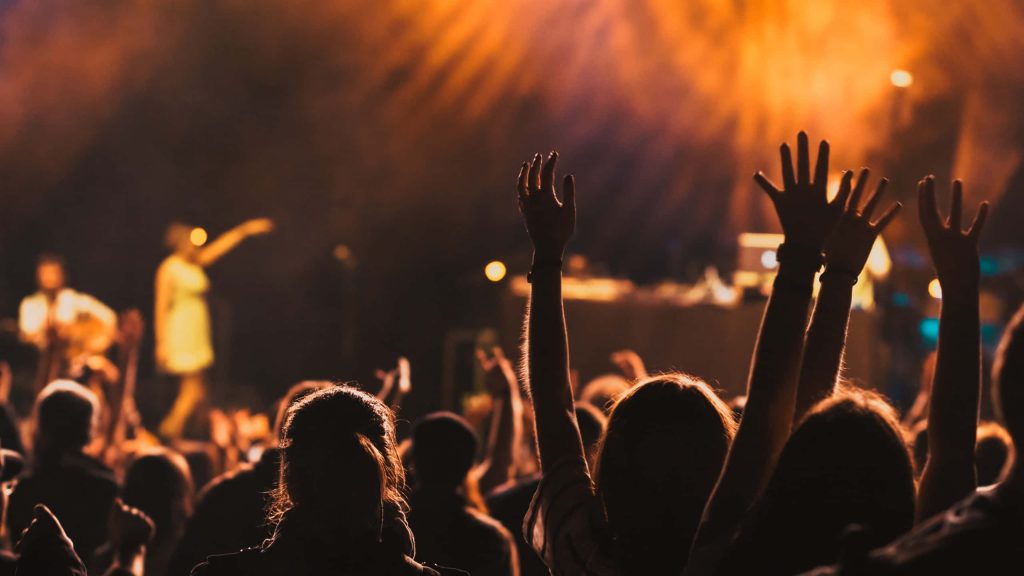 Concert wallpaper with silhouetted fans and warm amber stage lighting vibrant background