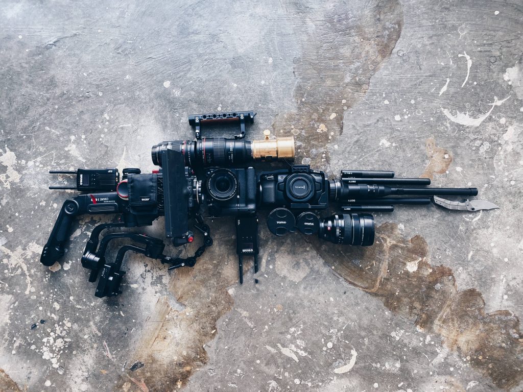 Flat lay of filmmaking gear arranged as rifle silhouette on concrete background wallpaper