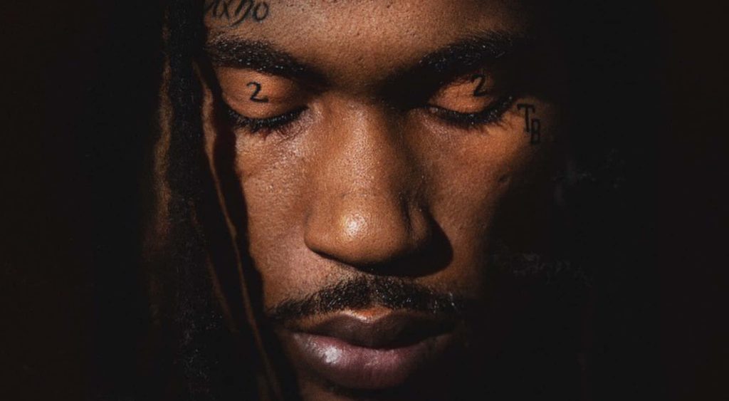 Cinematic close-up portrait of rapper Hunxho with face tattoos eyes closed moody background wallpaper