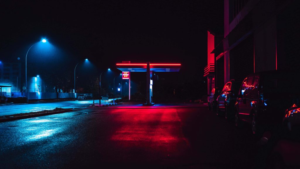 Cinematic neon night gas station wallpaper with glowing red canopy and blue streetlamps reflection