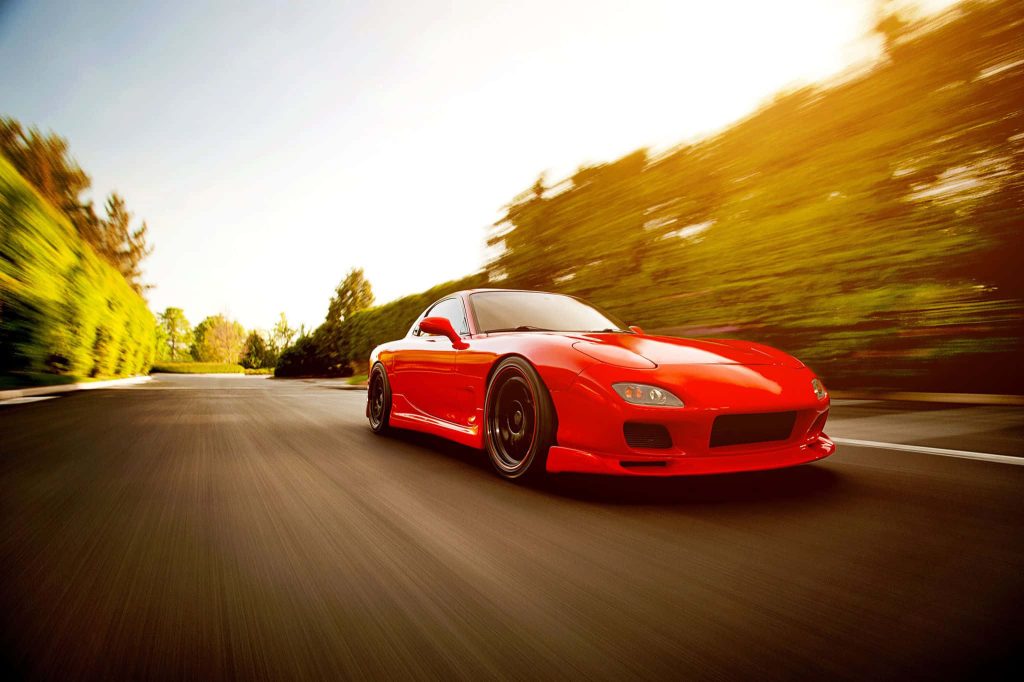 Red Mazda RX-7 FD3S speeding on sunlit tree-lined road cinematic JDM wallpaper background