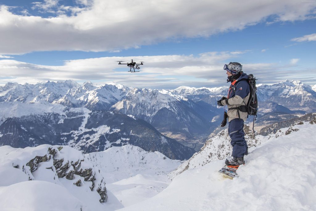 Snowboarder on snowy ridge with icy peaks under bright blue sky panoramic alpine landscape Wallpaper