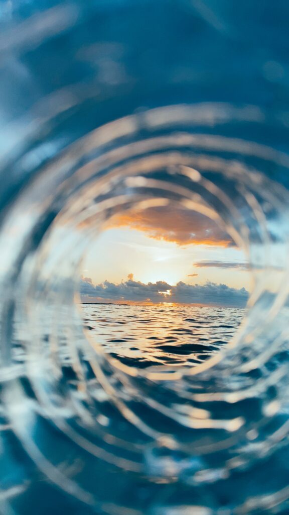 Circular view of waves and vibrant sunset sky with dramatic clouds over calm ocean at dusk Wallpaper