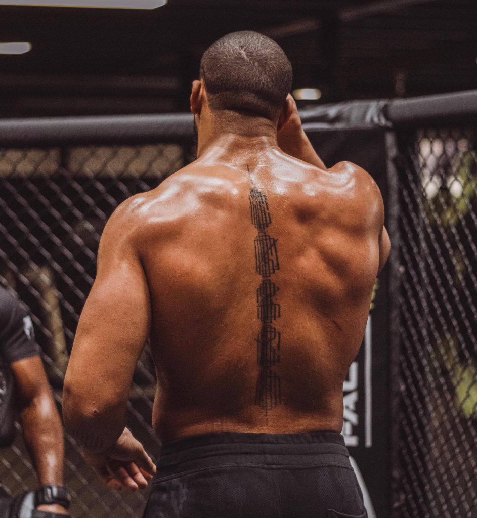 UFC heavyweight Ciryl Gane's muscular back with geometric spine tattoo in MMA cage wallpaper