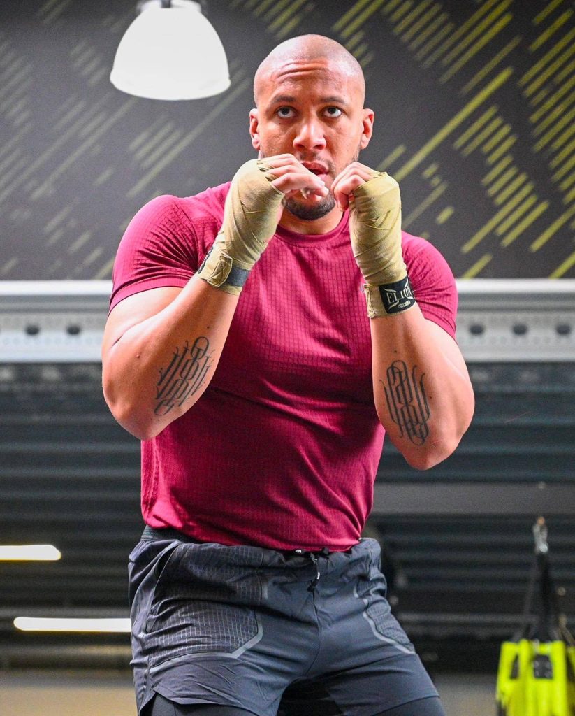 UFC heavyweight Ciryl Gane focused in maroon shirt and hand wraps in gym wallpaper background