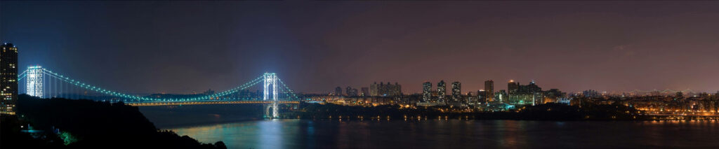 Urban Nightscape: A Captivating View of Skyscrapers, City Lights, and Illuminated Bridge on a Triple Monitor Setup Wallpaper