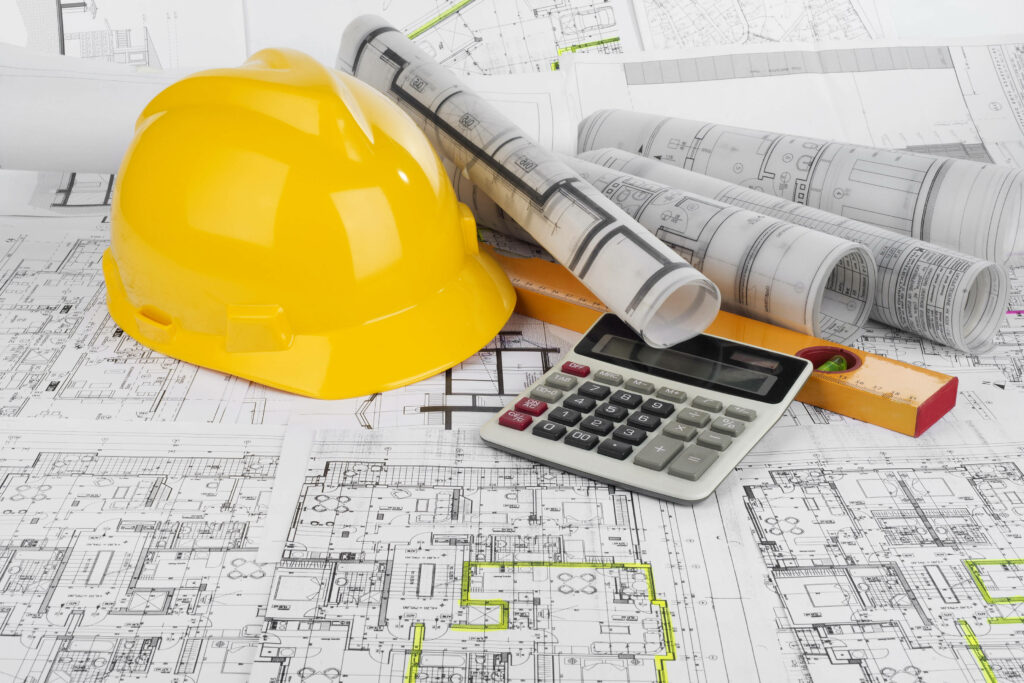 Yellow safety helmet with architectural blueprints calculator and measuring scale on desk Wallpaper